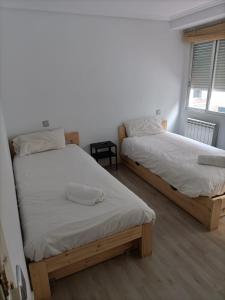 1 dormitorio con 2 camas y ventana en Príncipe habitaciones, en Madrid
