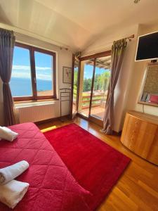 1 dormitorio con cama roja y ventana grande en VILLA LOVRAN - 150m to the beach - infinity pool - incredible sea view - Fitnessraum, en Lovran