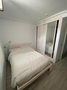 1 dormitorio con 1 cama blanca grande y espejo en Príncipe habitaciones en Madrid