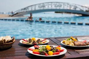 tres platos de comida en una mesa cerca de una piscina en Sea view apartment Kaliakria resort, en Topola