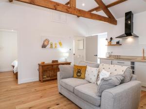 a living room with a couch and a kitchen at Pear Tree Cottage in Saltash