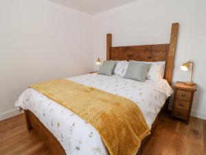 Schlafzimmer mit einem großen Bett mit einem Kopfteil aus Holz in der Unterkunft Pear Tree Cottage in Saltash