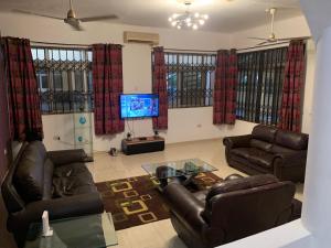 ein Wohnzimmer mit 2 Ledersofas und einem TV in der Unterkunft Accra Service Villas- 3 in Spintex