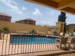 a swimming pool with chairs and a fence at Accra Service Villas- 3 in Spintex