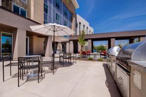 un patio al aire libre con mesas, sillas y una sombrilla en Home2 Suites By Hilton Petaluma, en Petaluma