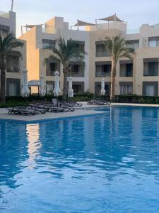 une piscine avec des chaises et des parasols et un bâtiment dans l'établissement Mangroovy - Delicate 1BR Ground floor by the Pool, à Hurghada