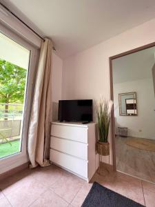 a living room with a tv and a window at Appartement 10 MIN de Disneyland Paris in Montévrain