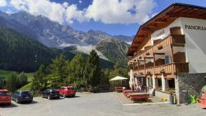 un hotel con auto parcheggiate in un parcheggio con montagne di Pension Panorama a Solda