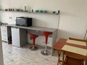 a kitchen with a desk with a microwave and red stools at Hermoso departamento en Villa María in Villa María