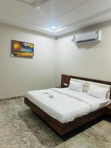 HOTEL SKYZ في Sirsa: غرفة نوم بسرير وملاءات بيضاء وصورة على الحائط
