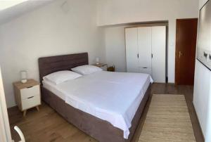 a bedroom with a large white bed and a wooden floor at Apartman Marla in Sevid
