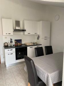 a kitchen with a table and chairs and white cabinets at Apartman Marla in Sevid +15 photos