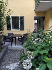 een patio met een tafel, stoelen en bloemen bij Il Giardino nascosto in Omegna