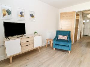 a living room with a tv and a blue chair at Meadow Bay in Bideford