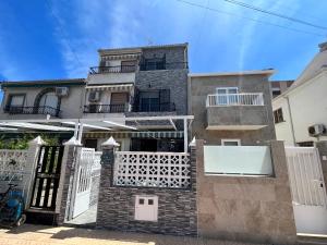 ein Haus mit einem weißen Tor und einem Gebäude in der Unterkunft Prachtig gemoderniseerde woning op 250 meter van het strand in Santa Pola