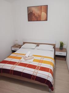 - une chambre avec un lit et une couverture rayée dans l'établissement Apartmani Petra, à Primošten