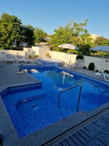 a large swimming pool with chairs and an umbrella at Apartman PAOLA in Vrh