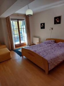 Apartment Mathis & MTB-garage في ياخيموف: غرفة نوم بسرير كبير مع بطانية ارجوانية