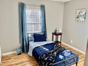 Schlafzimmer mit einem Bett mit blauer Bettwäsche und einem Fenster in der Unterkunft Reed Legacy, LLC Home in Newark