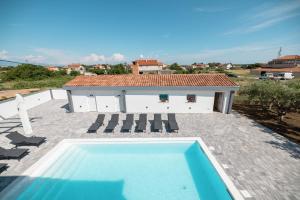a swimming pool on a patio with a house at Villa Matea in Nin