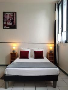ein Schlafzimmer mit einem großen Bett mit zwei roten Kissen in der Unterkunft Studio confortable in Rochefort