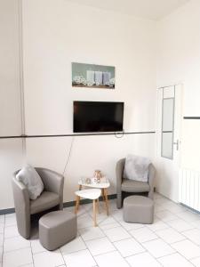 een woonkamer met 2 stoelen, een tafel en een tv bij Studio confortable in Rochefort