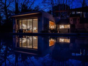 a house with its reflection in the water at night at Maison La Roselière in Montpellier