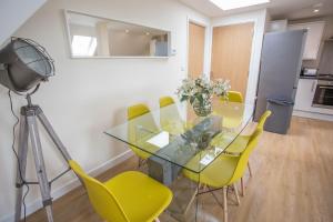 une salle à manger avec une table en verre et des chaises jaunes dans l'établissement Bicester Road Apartments, à Kidlington