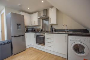- une cuisine avec des placards blancs et un lave-linge/sèche-linge dans l'établissement Bicester Road Apartments, à Kidlington