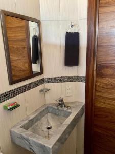 a bathroom with a stone sink and a mirror at Casa Balam in Rincon de Guayabitos