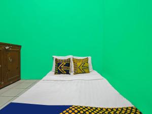 un letto con due cuscini in una stanza con una parete verde di SPOT ON 92610 Barokah Kostel Syariah a Semarang