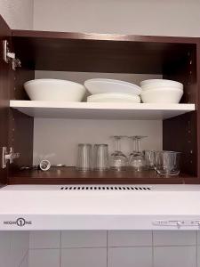 a kitchen shelf with bowls and dishes on it at Appartement DisneyLand Montevrain in Montévrain