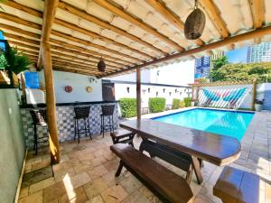 a patio with a wooden table and a swimming pool at Ponta Negra Temporada in Natal