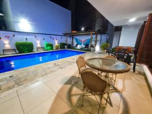 a patio with a table and chairs next to a swimming pool at Ponta Negra Temporada in Natal