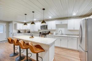 una cocina con armarios blancos y una gran isla con taburetes. en Expansive Cedar Hill Rental with Pool and Hot Tub!, 