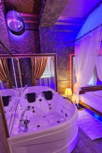 a white bath tub in a room with purple lighting at Hotel Boutique Mikaela (Adult Only) in Braşov