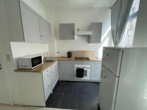 una piccola cucina con armadietti bianchi e forno a microonde di Apartment Brussels 1 a Bruxelles