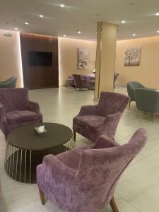 um átrio com cadeiras, uma mesa e uma televisão em Fiori Hotels em Taif