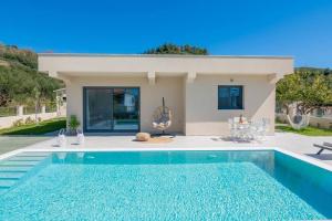 a villa with a swimming pool in front of a house at Villa Adiola, An Unrivalled Retreat in Kalamaki