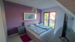 a purple bedroom with a bed and a window at Ostoja Rydzewo A in Rydzewo