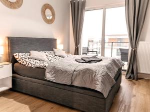 een slaapkamer met een groot bed en een groot raam bij Bridge Apartments&Spa apartament LILKA in Dziwnów