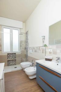 łazienka z 2 umywalkami, toaletą i wanną w obiekcie Ci Vuole Leggerezza Apartment Free Parking w Bolonii