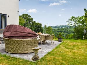 a patio with a table and chairs in the grass at Bryn Bannon in Cilcain
