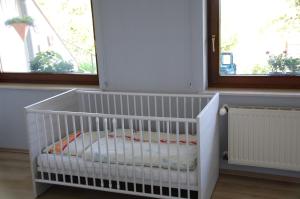 ein weißes Kinderbett in einem Zimmer mit zwei Fenstern in der Unterkunft Ferienwohnung Hoffmann in Osburg