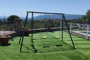 a swing set on a lawn with a pool at Casa El Calderon in Chella