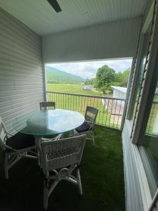 a patio with a glass table and chairs on a porch at Unique Condo on flight park! Watch hangliders fly! in Wildwood