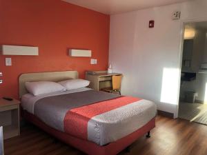 a bedroom with a bed with an orange wall at Motel 6-Goodlettsville, TN - Nashville in Goodlettsville