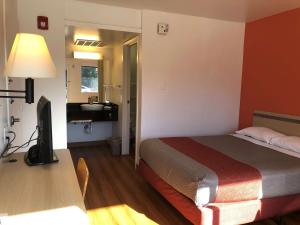 a hotel room with a bed and a desk with a television at Motel 6-Goodlettsville, TN - Nashville in Goodlettsville
