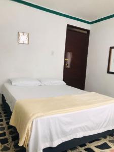 um quarto com uma cama com um cobertor branco em Hostal la 18 em Pereira