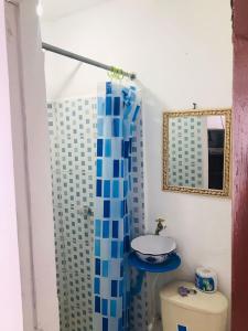 y baño con cortina de ducha azul y aseo. en Hostal la 18, en Pereira